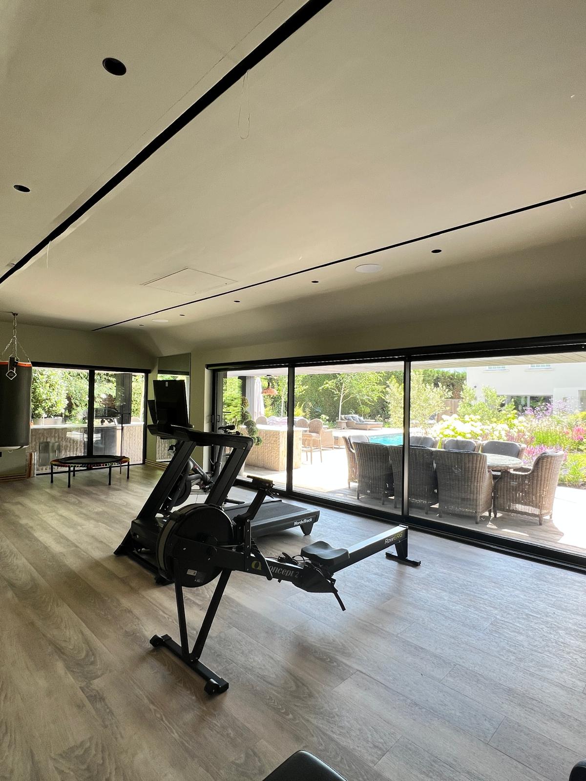 Inside the garden gym: rowing machine and glazed doors onto the pool deck
