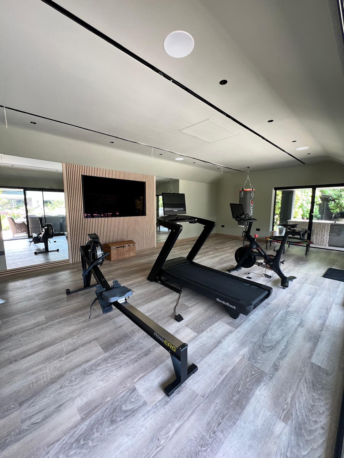 Garden gym interior with treadmill, TV wall and full-height glazing