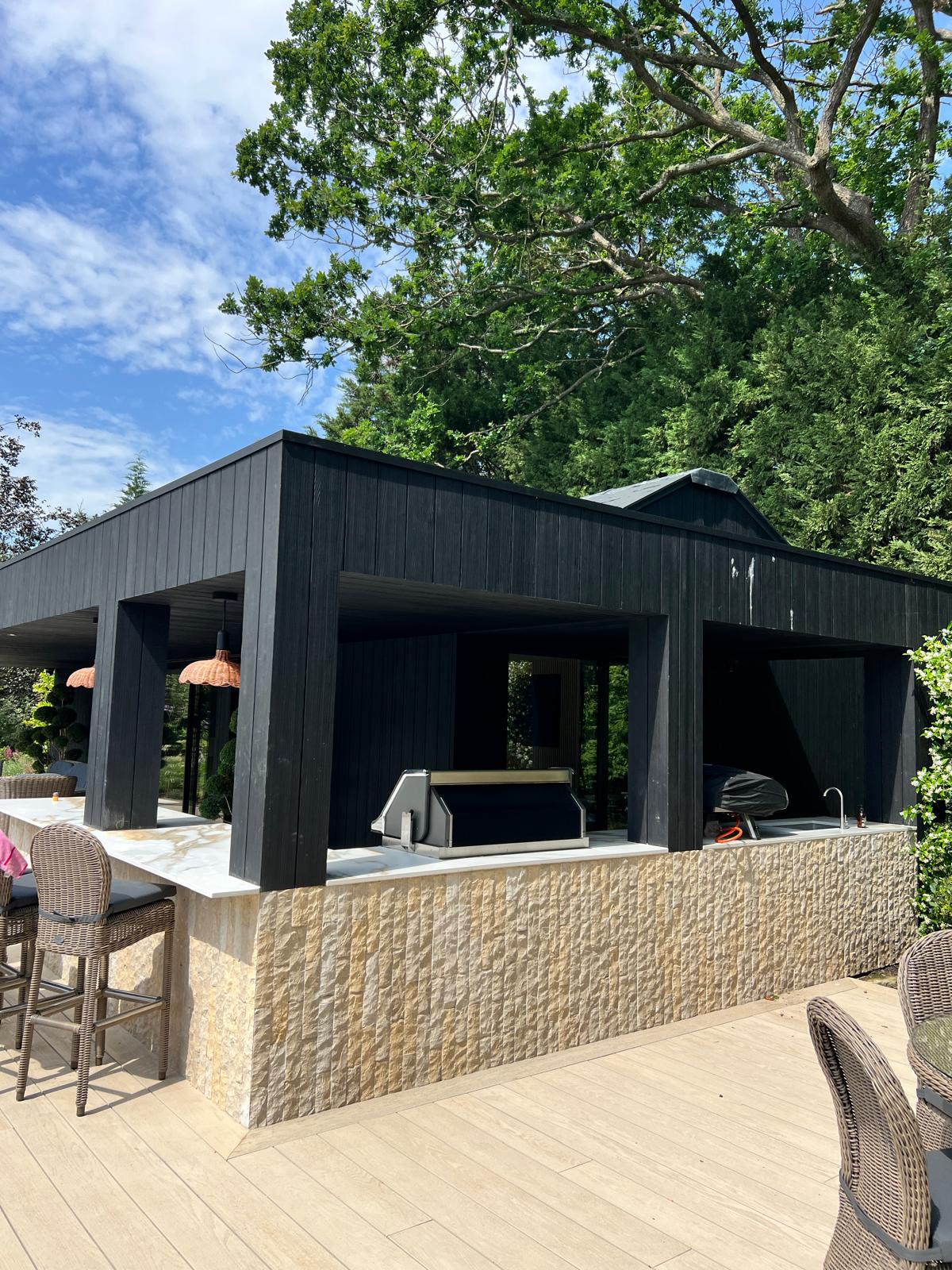 Black timber-clad garden gym with covered BBQ and bar area