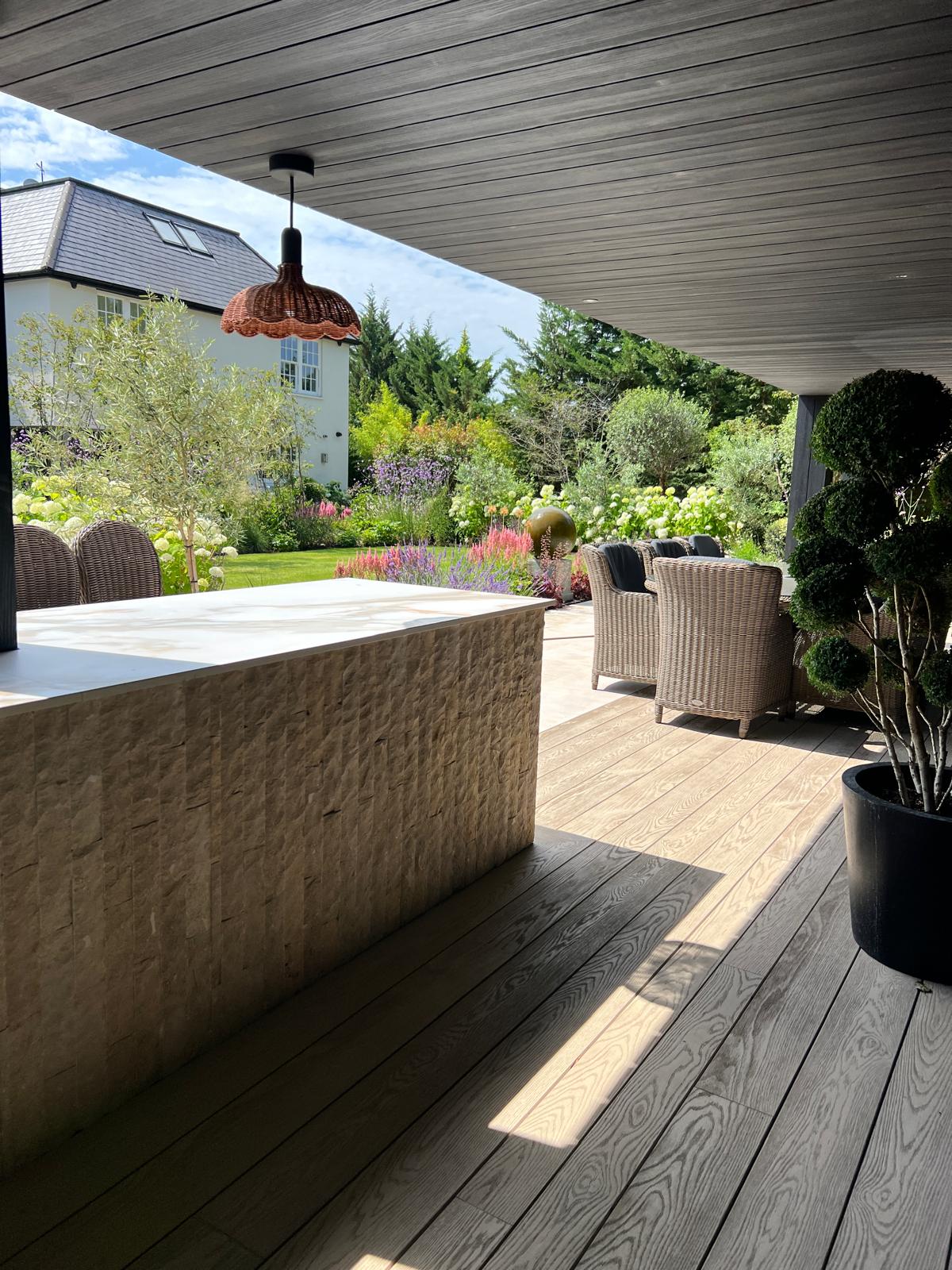 Stone-faced outdoor bar with pendant lights and rattan seating