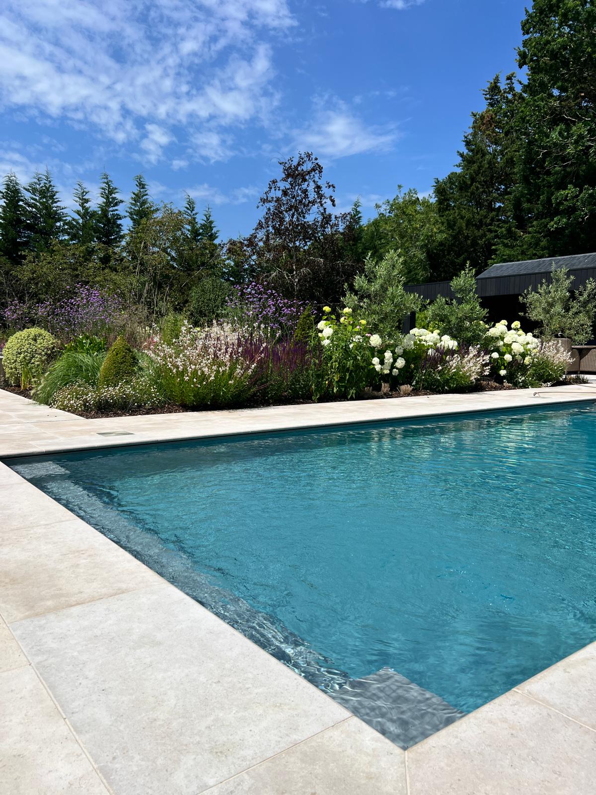 New swimming pool with stone surround and planting
