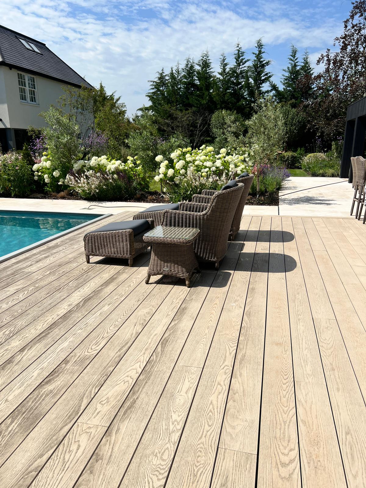 Pool deck with loungers looking back towards the garden